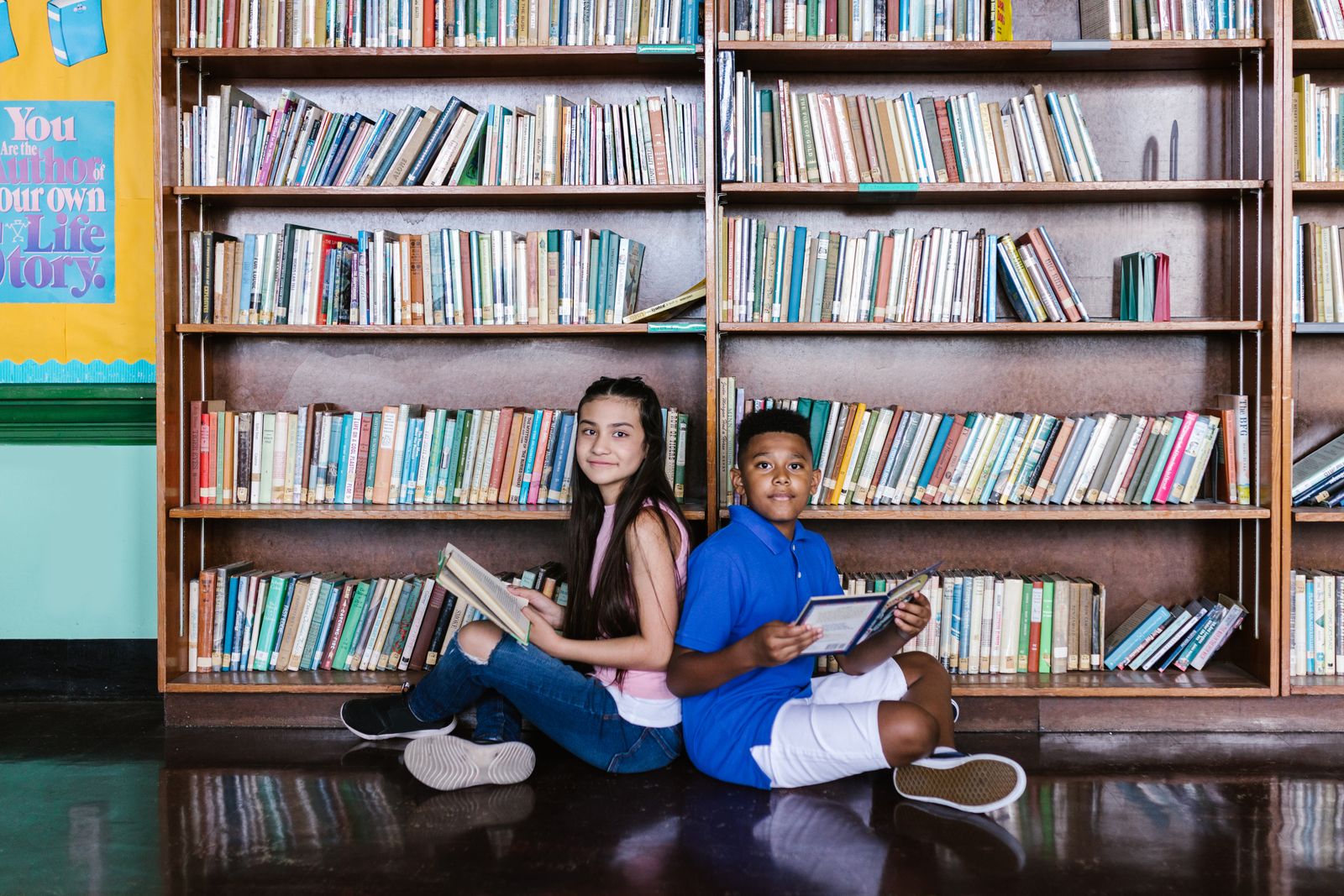 Two children sitting on the floor holding books